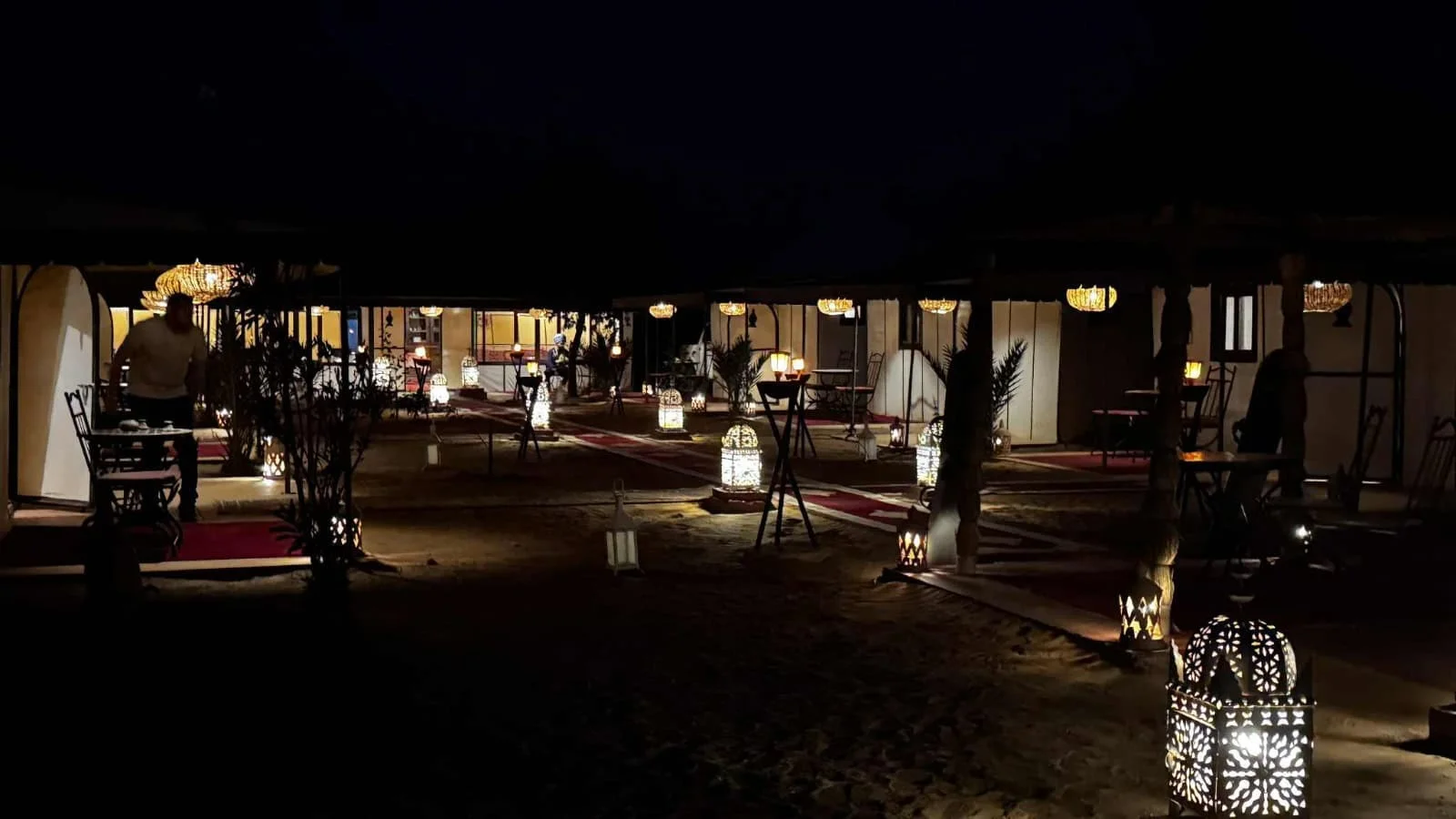 Luxurious desert camp setup in Merzouga at night with ambient lighting.